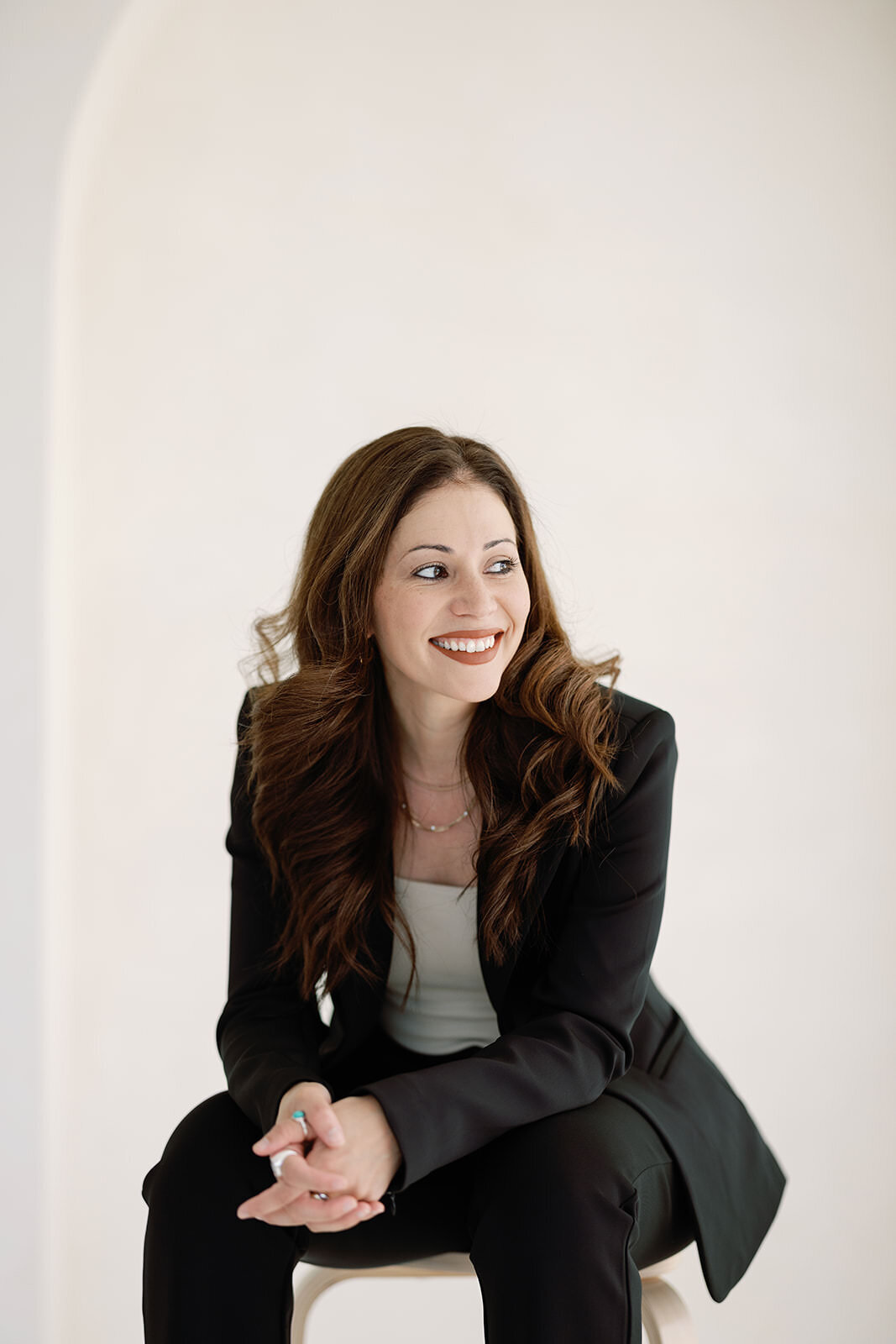 Professional woman smiling in a sleek black suit during a luxury headshot session in Washington, DC.