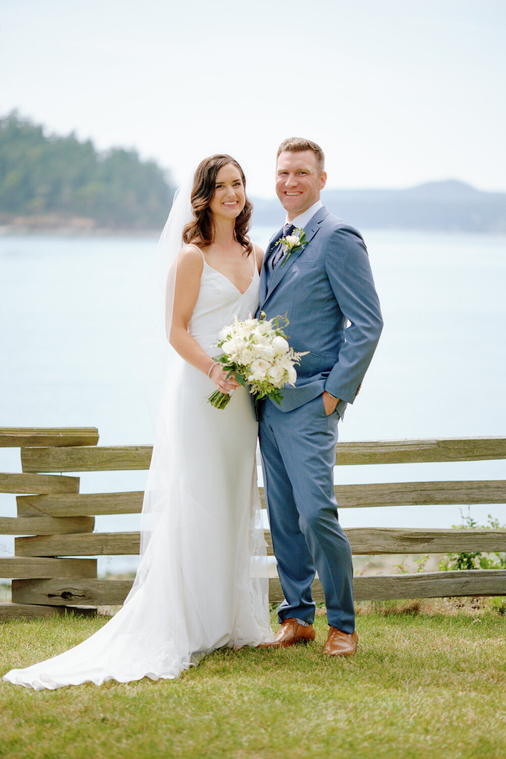 Bride and groom hold hands with the puget sound behind them