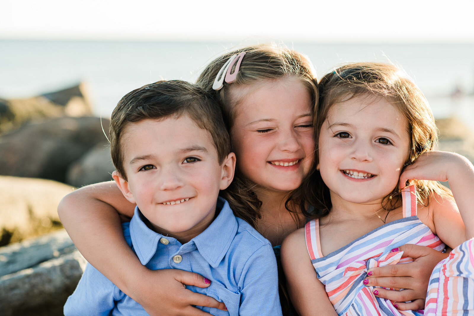 kids snuggling on rocks at beach