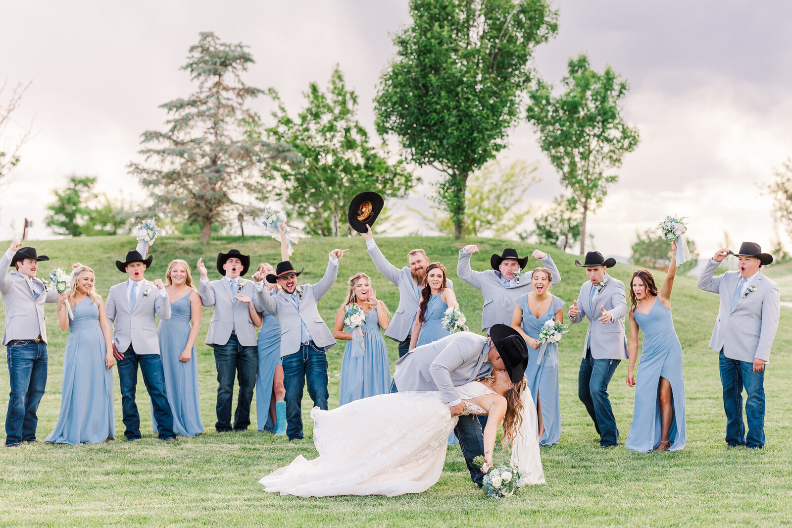 Groom dipping his bride for a kiss in front of their cheering bridal party at a Loma, Colorado wedding