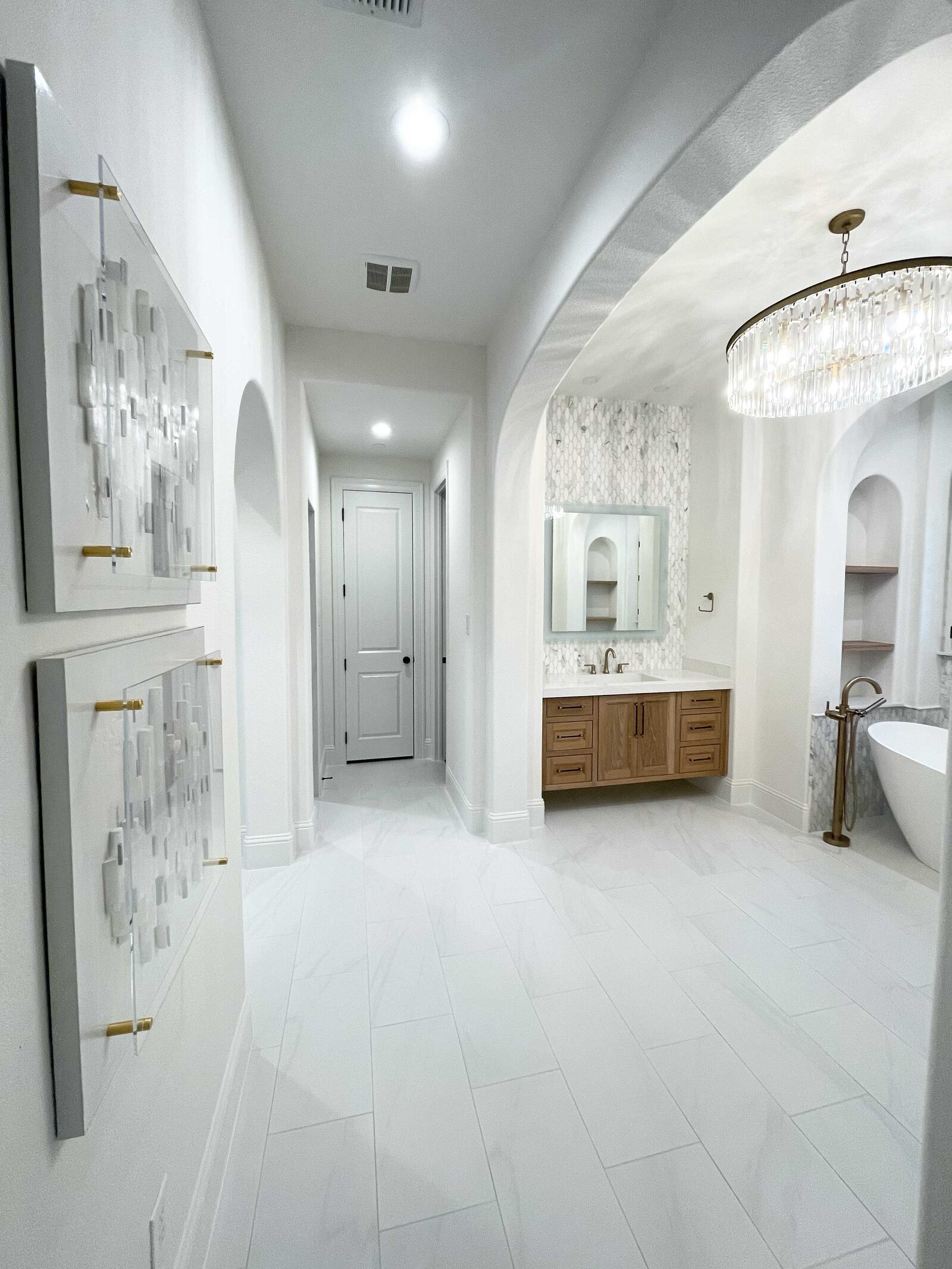 Residential interior design in Frisco, featuring a spacious white bathroom decorated with incredible artwork and gold accessories around the tub.