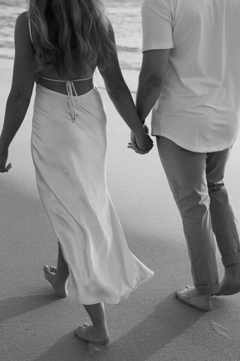 couple holding hands and walking along beach in naples florida