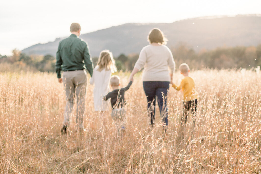 Family of five walking in field with mountains