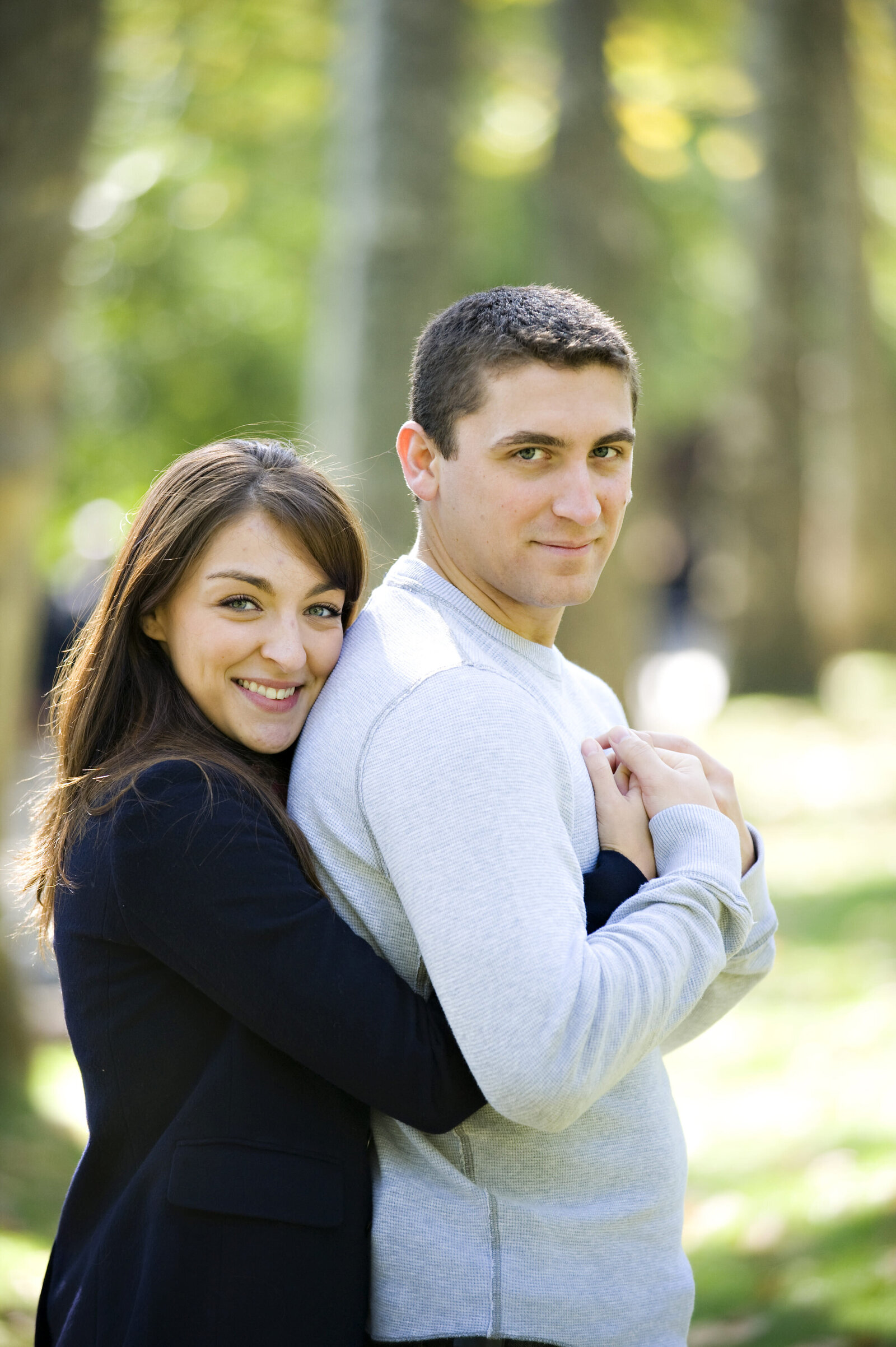 A person standing behind their partner with their arms wrapped around them 