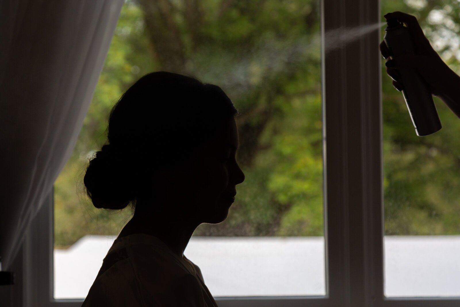 silhouette of bride finishing up hair