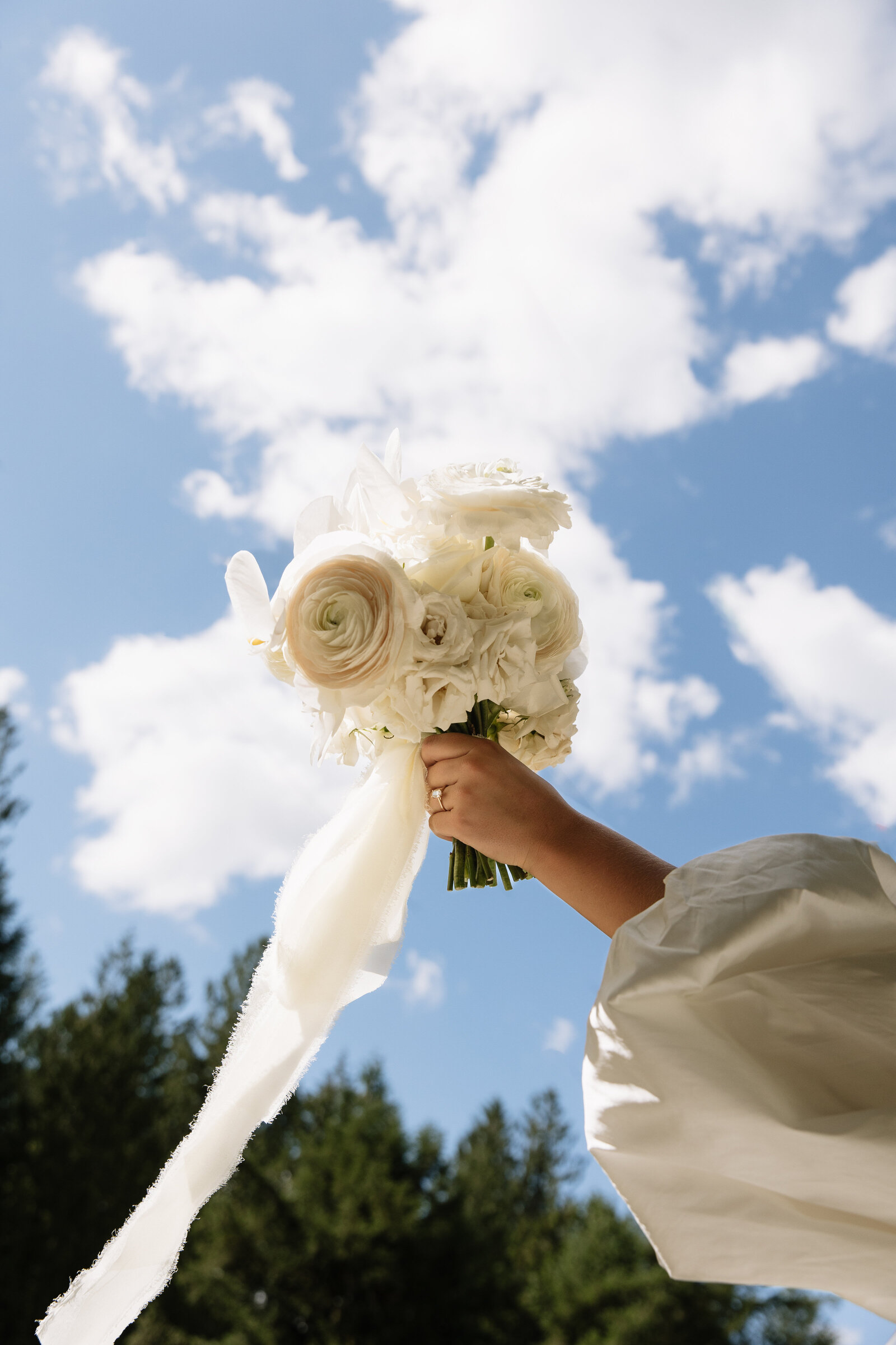 under view of bride holding her bouquet up to the sky