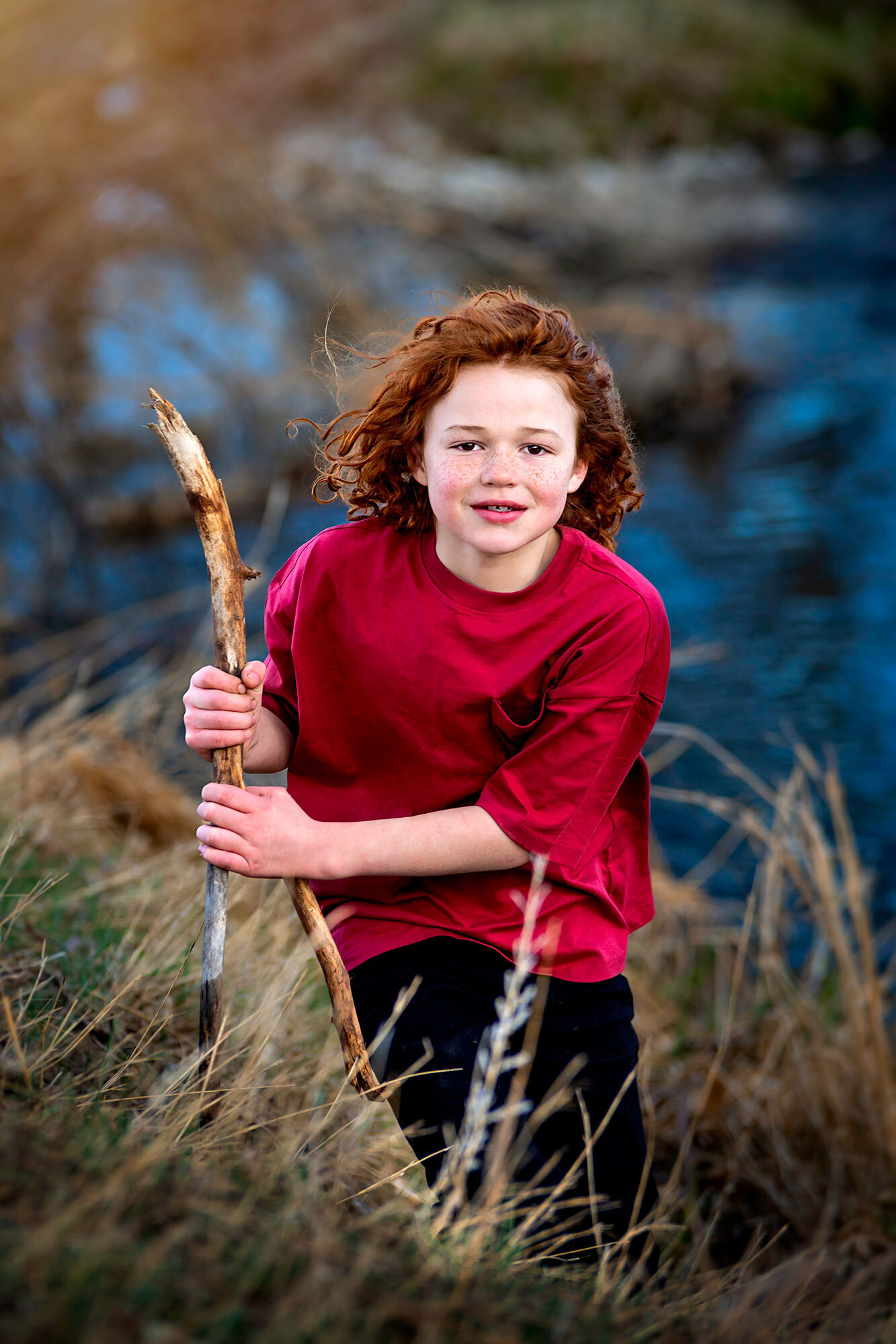 Sandstone-Park-Longmont-Colorado-red-hair-boy-curly-wavy-in-wind-freckles-stick-river-coloful-vibrant