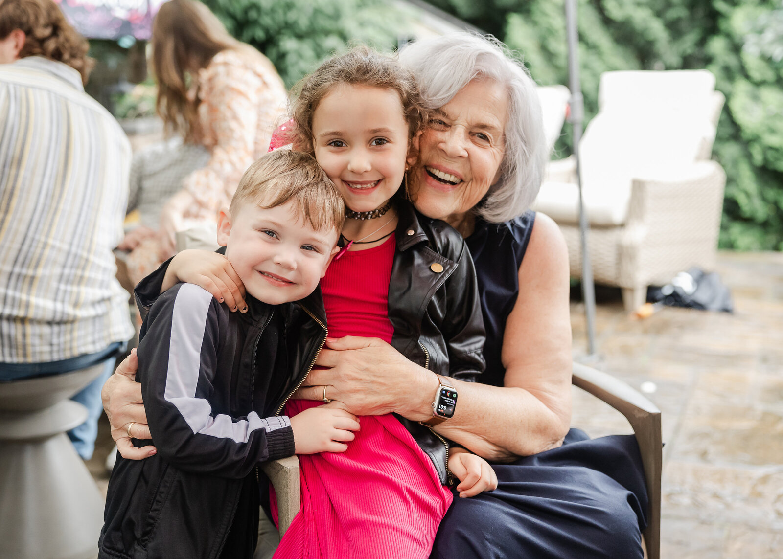 Grandma hugs grandkids at a casual backyard party.