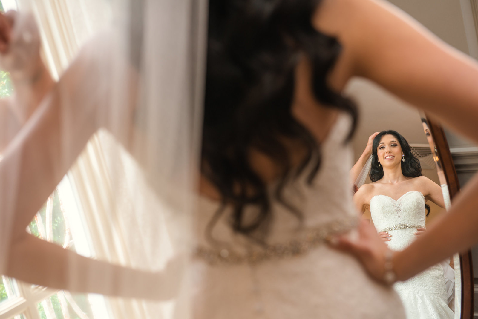 Bride putting her veil on at Glen Cove Mansion