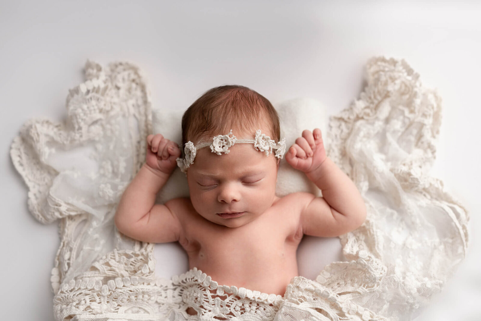 baby girl laying on her back with lace fabric wings