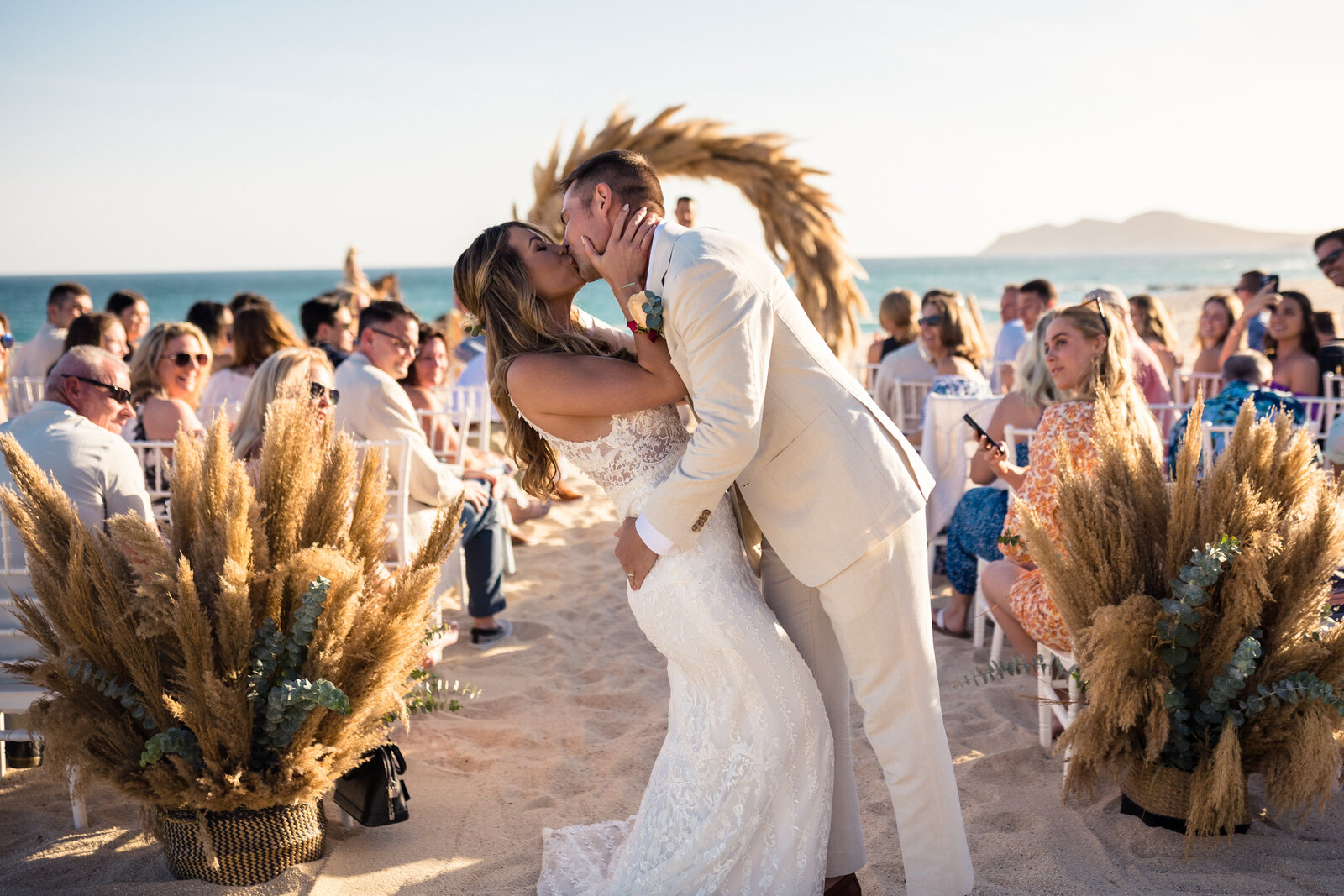Bride and groom kissing on beach in Cabo.