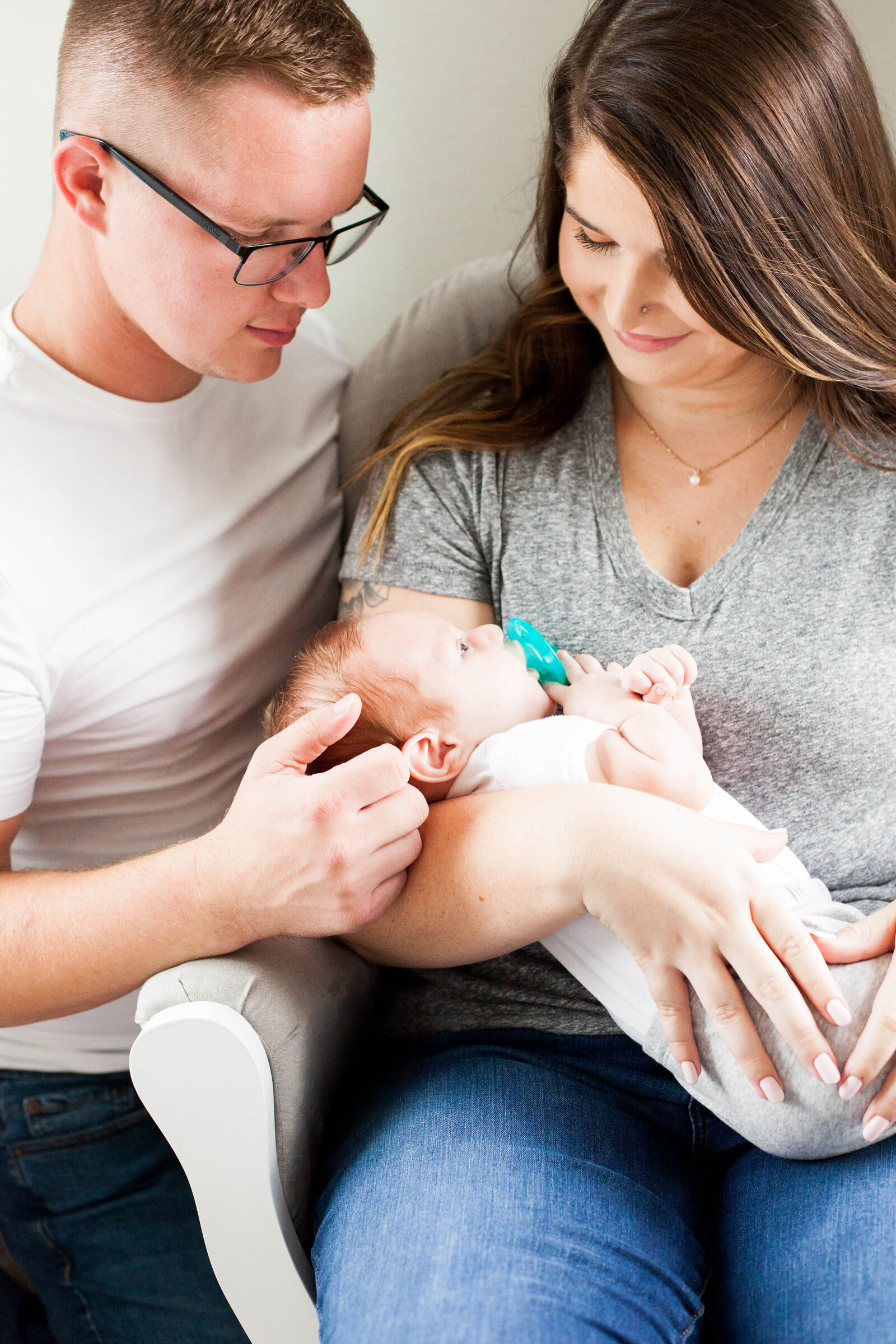 A young mother and father holding their newborn baby.