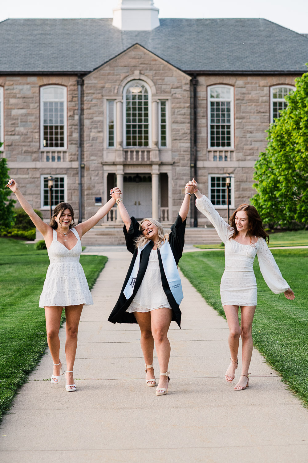 grad girls walk and hold hands in air