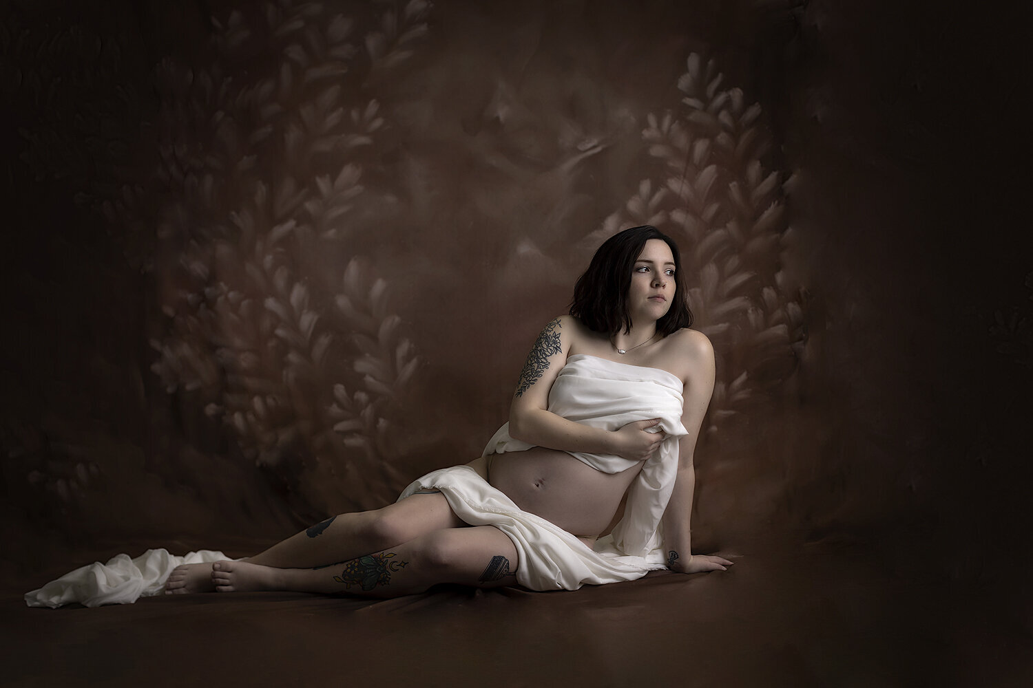 Woman poses with white cloth at maternity session.
