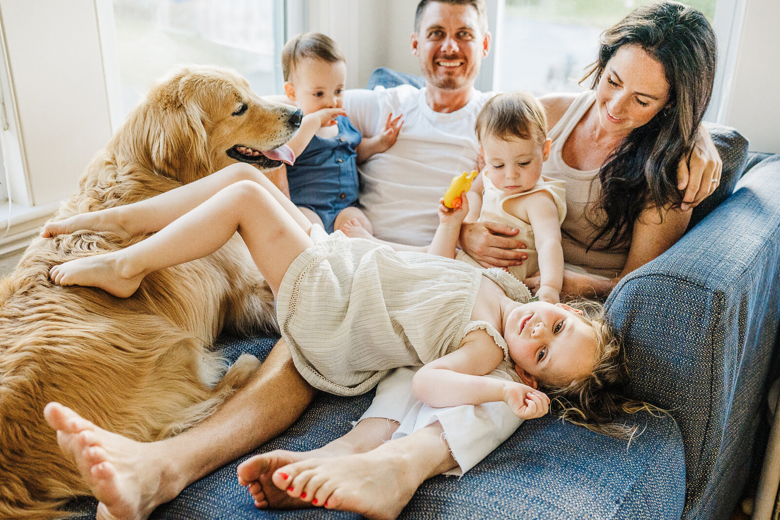 family lays on couch with kids and dog