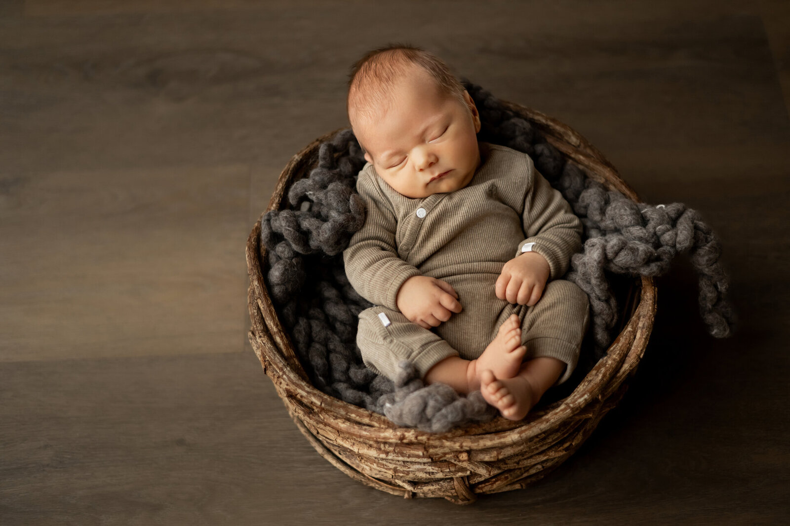 Newborn fotografie in Arnhem: slapende baby in rieten mandje met wollen dekentje tijdens een fotoshoot in Studio Laurant door Juliette Fotografie.
