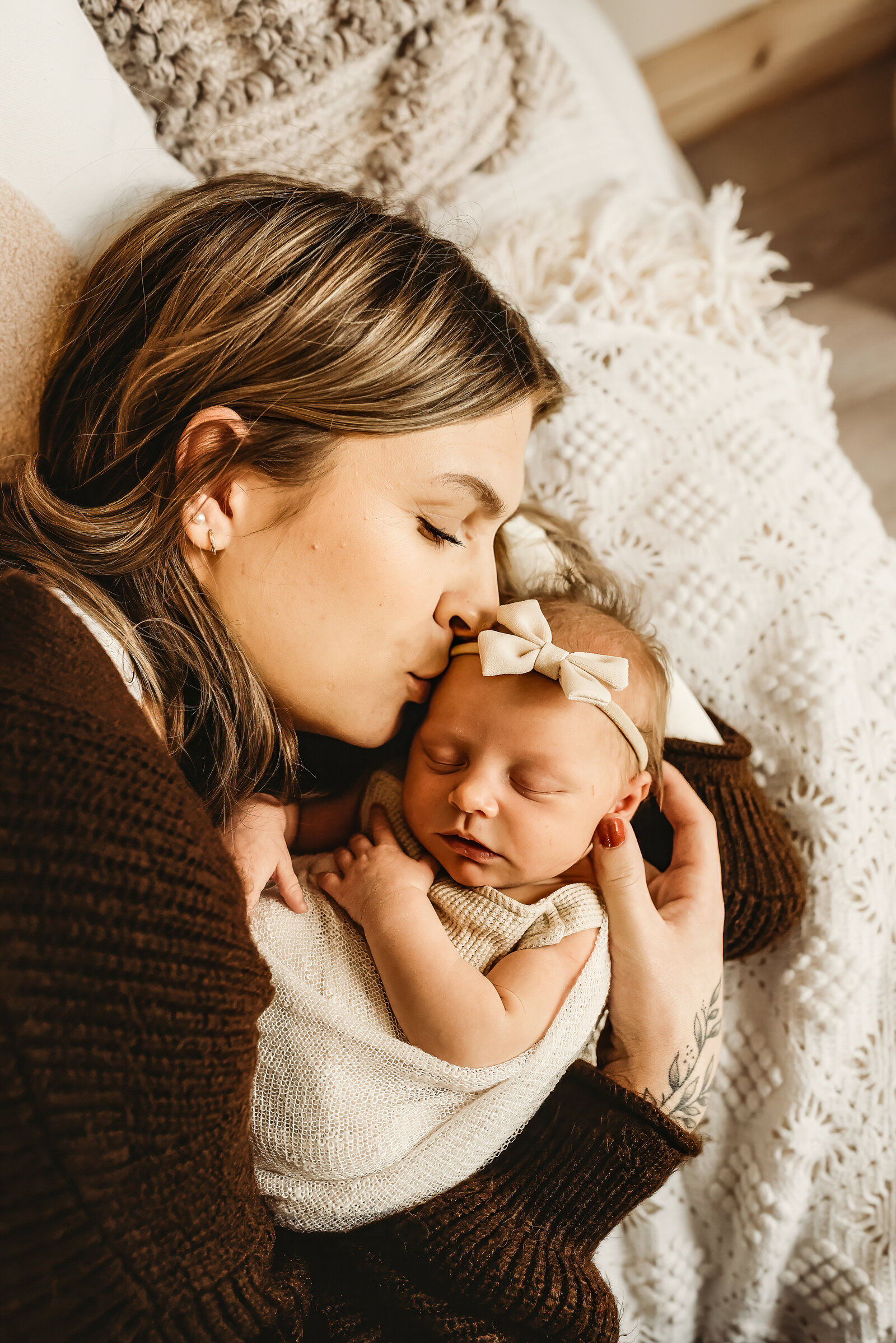 Holding tight to her newborn baby girl, a momma snuggles and gives a little kiss to someone so tiny that holds momma's whole heart. 