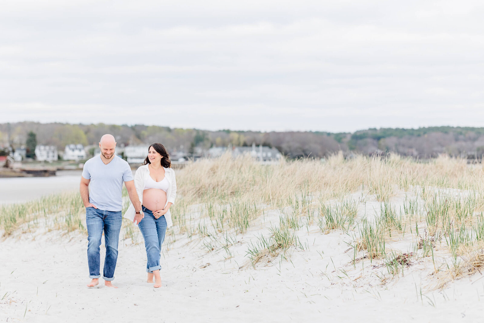 Pregnant woman with bare belly walks with her husband on a sandy path