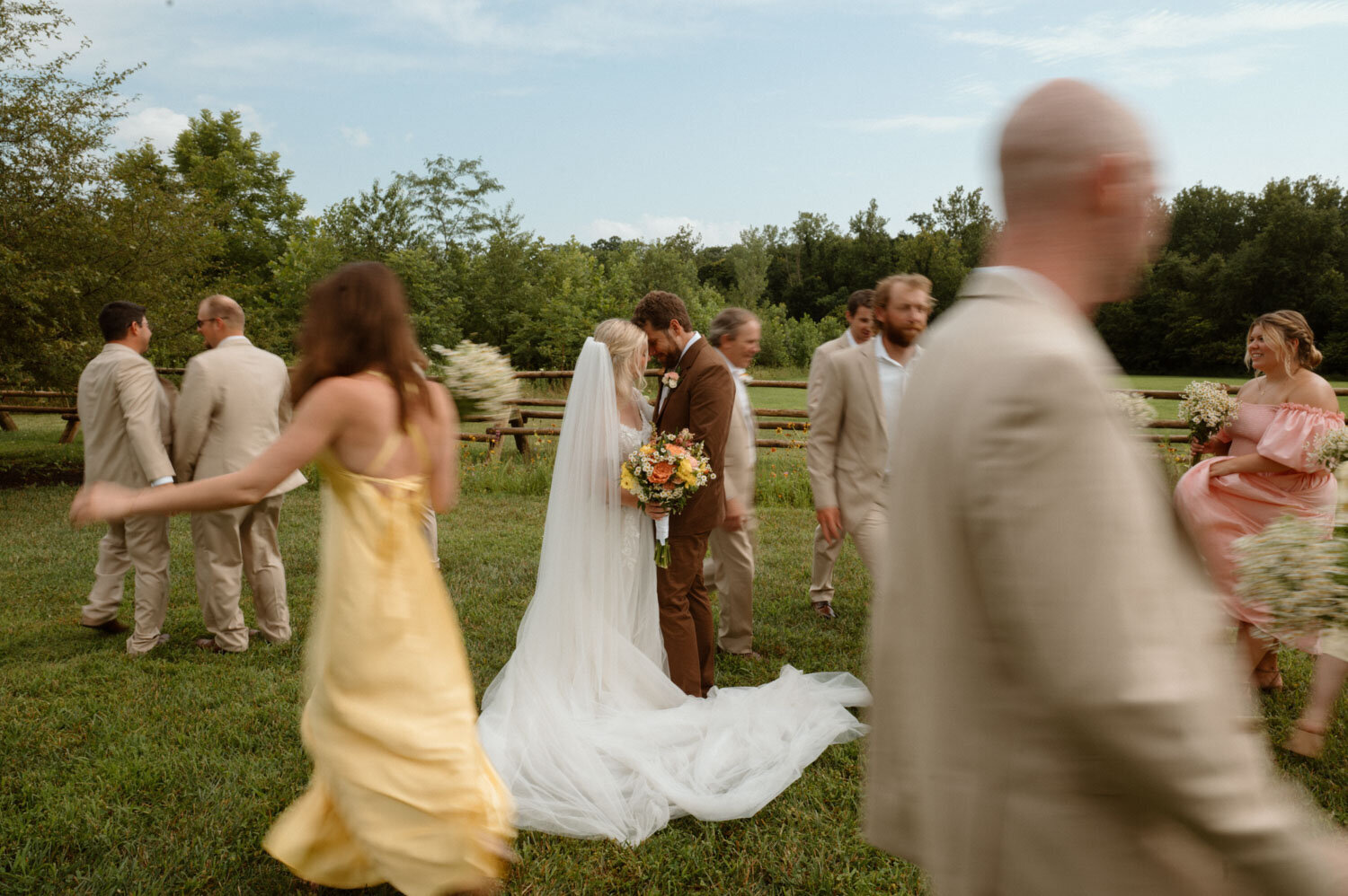 Bride and groom kissing in the center while entourage are walking
