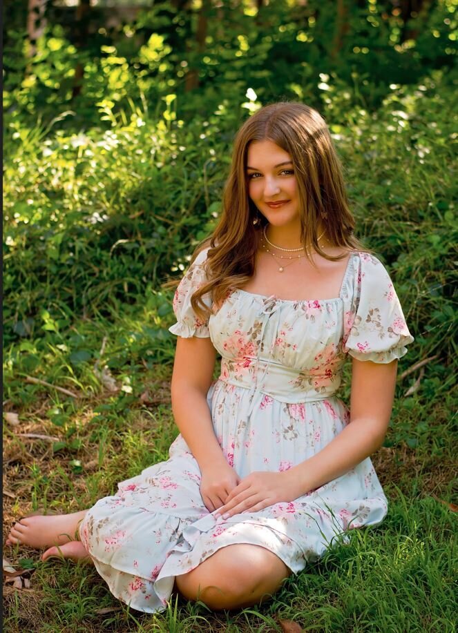 High School Senior sitting in the grass surrounded by plants in Redlands CA