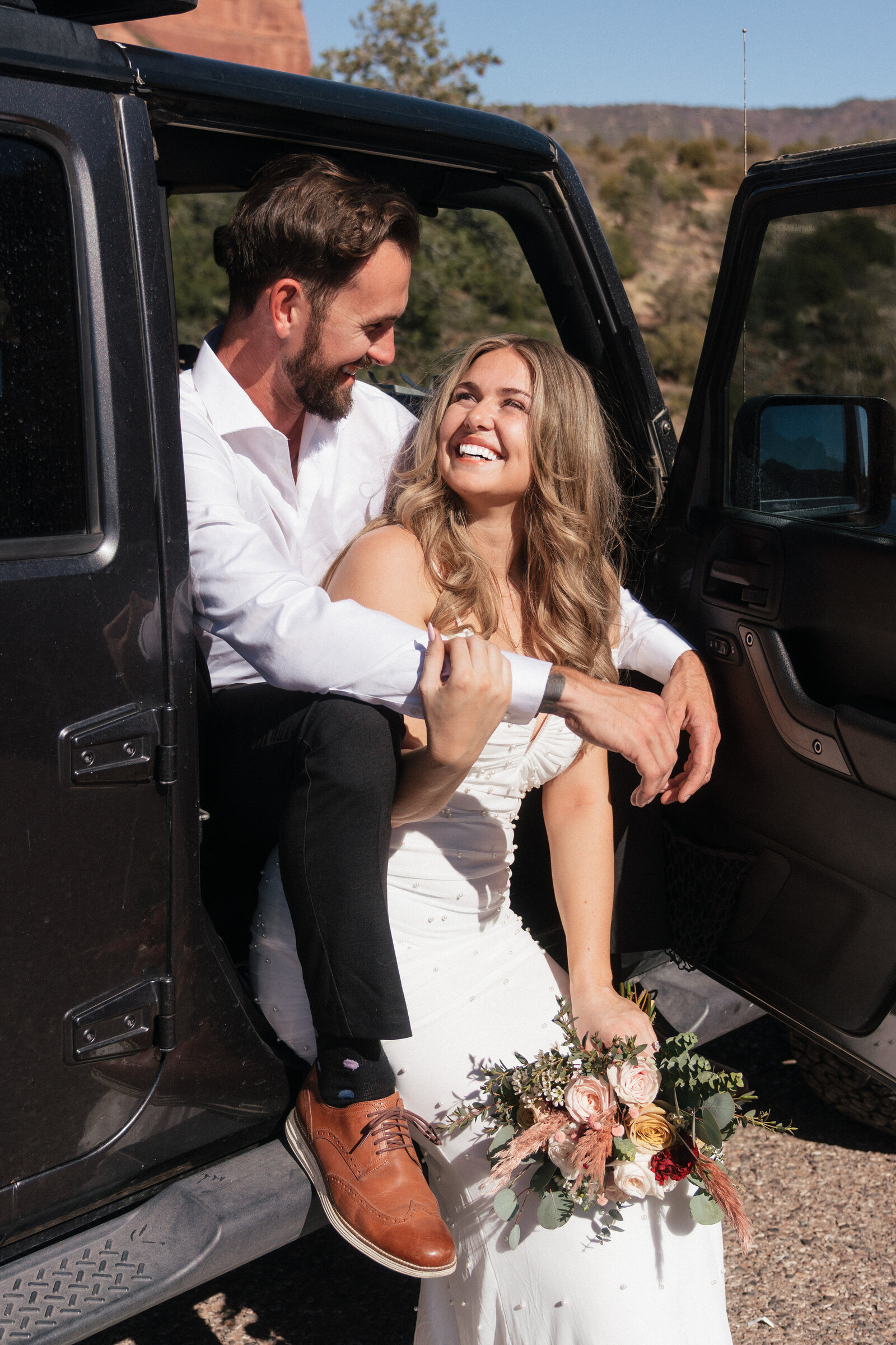 Bride and groom sharing a joyful moment in their Jeep during a Sedona elopement at Merry Go Round Rock.