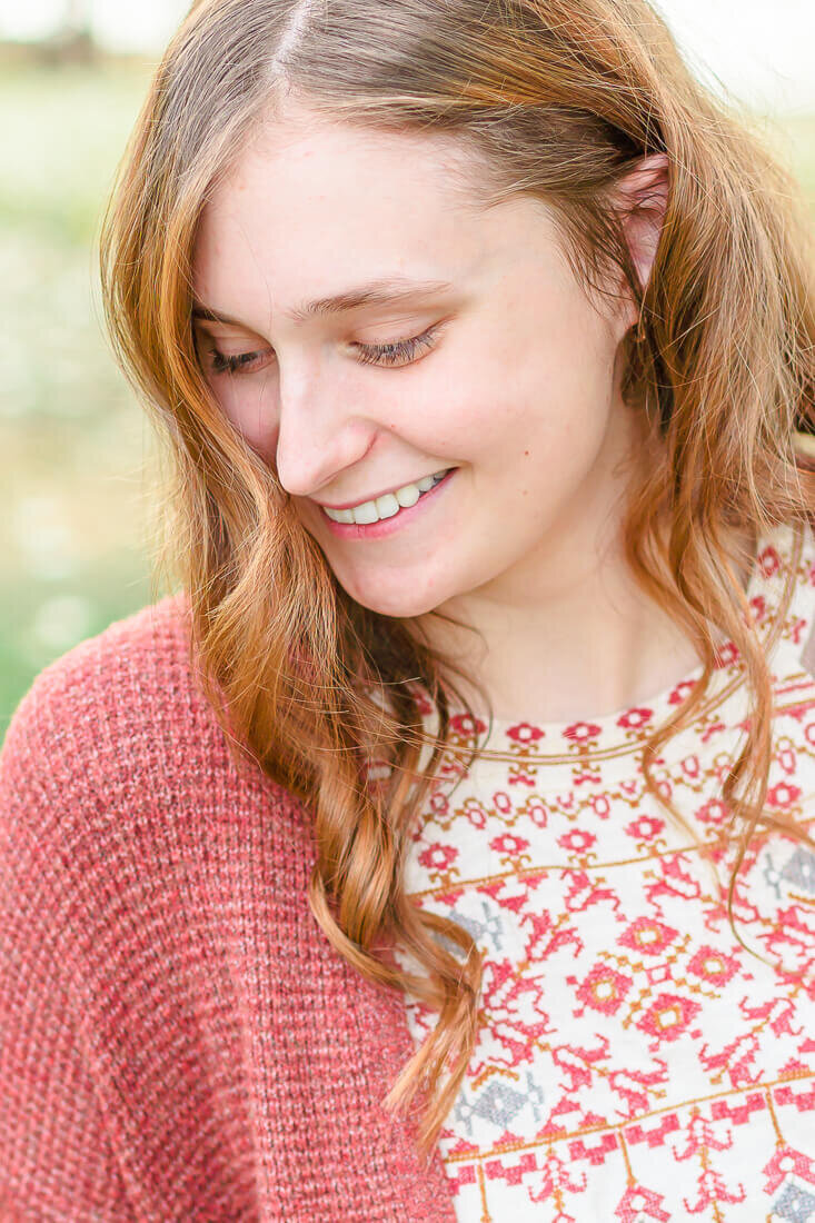 Closeup of a high school senior girl wearing a rust colored sweater. Captured at Sugar House Park in Salt Lake City in the Fall