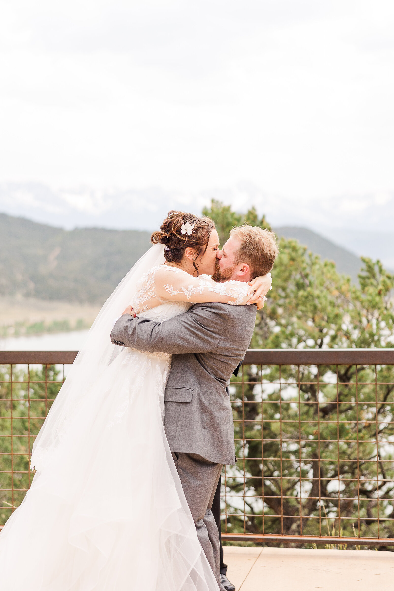 Bride and groom sharing their first kiss as newlyweds at a Ridgway State Park wedding, surrounded by family and friends