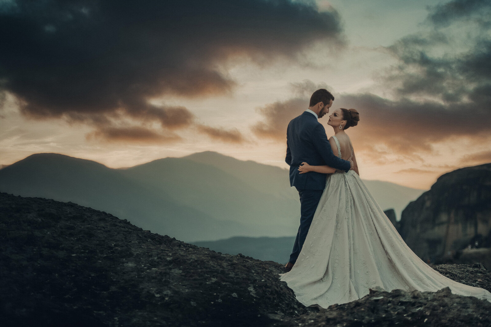 Bride and groom facing each other with a mountain and sunset view