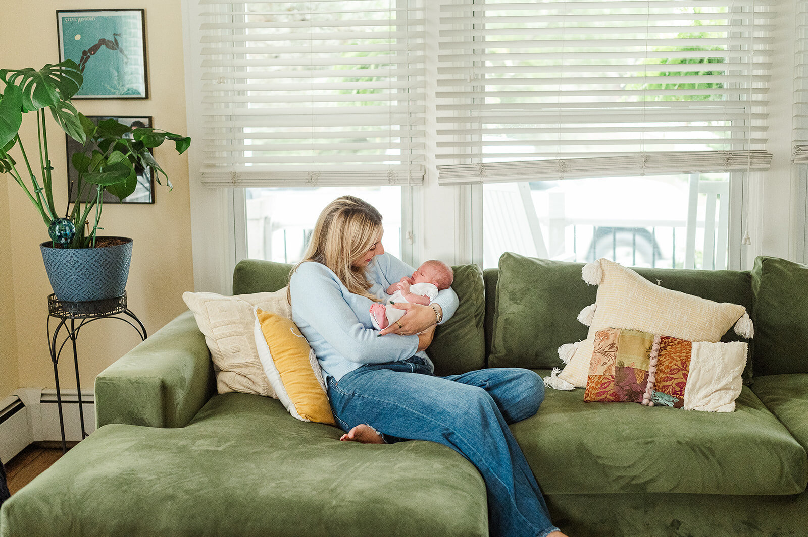 mother sitting on a green couch with her newborn during an at home newborn session york pa