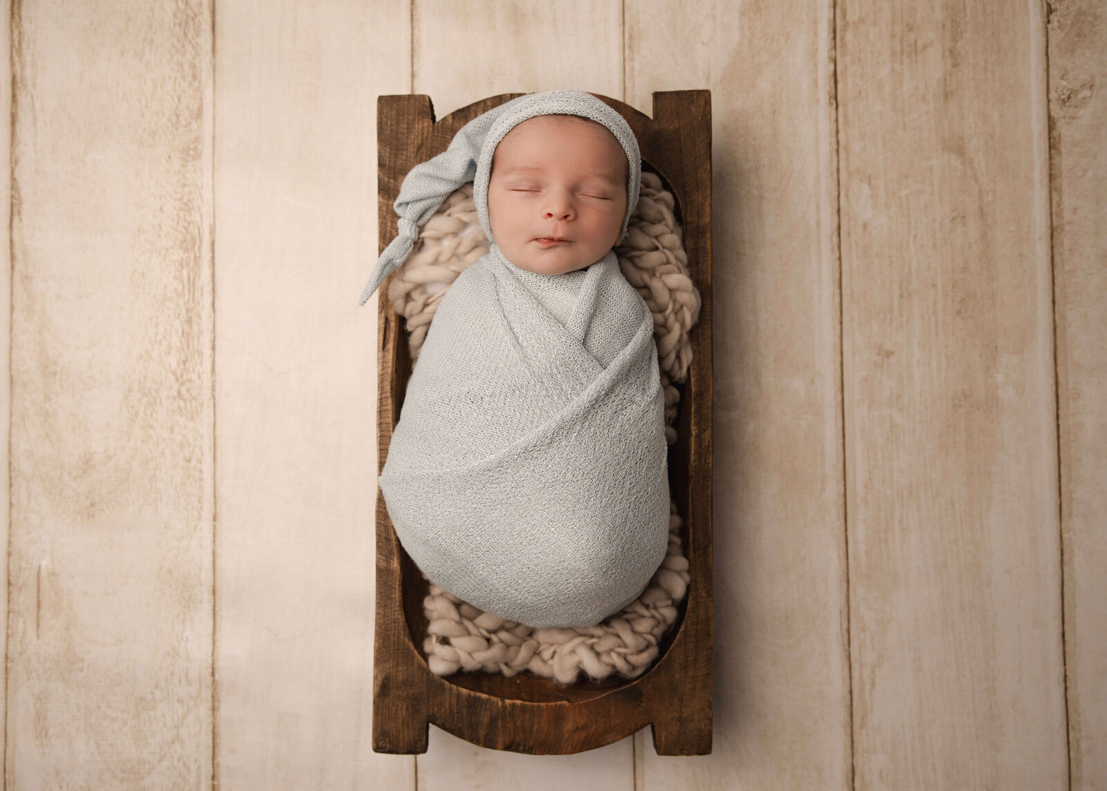 Baby boy sleeping in  wood trench bowl  in studio newborn session by Ashley Nicole Photography.