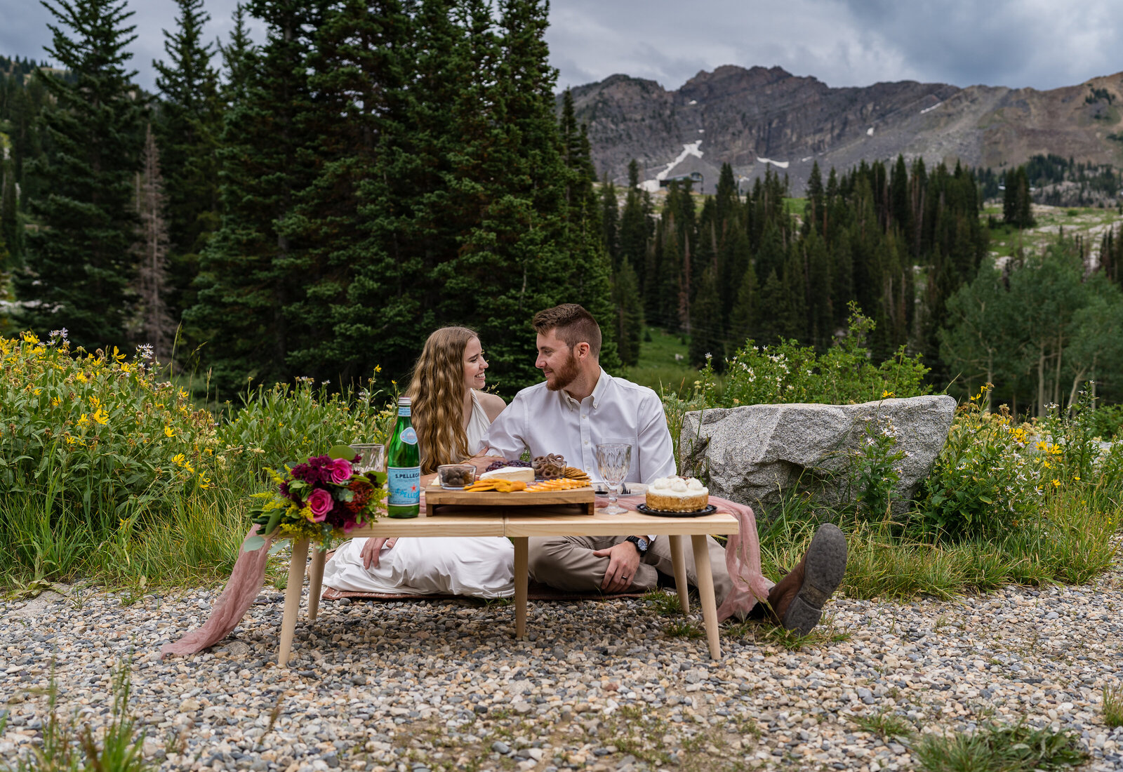 Bride and groom looking at each surrounded by the mountains near Salt Lake City, Utah having a quiet picnic just the two of them to celebrate their elopement.