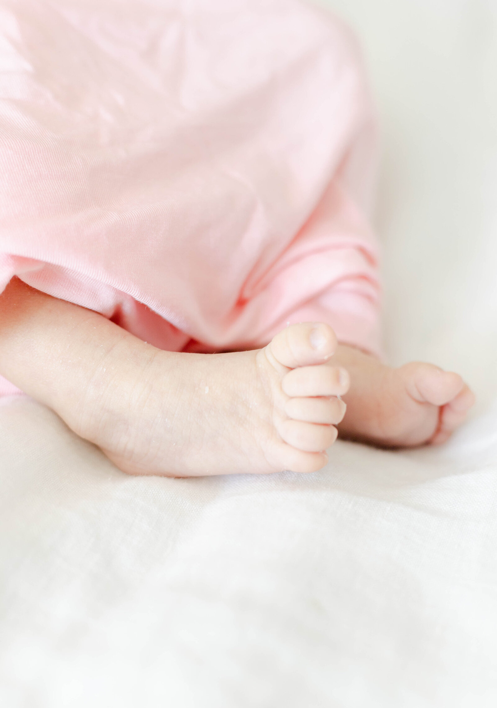 A Savannah newborn photographer captures  beautiful details of a baby girl laying on a white bed.