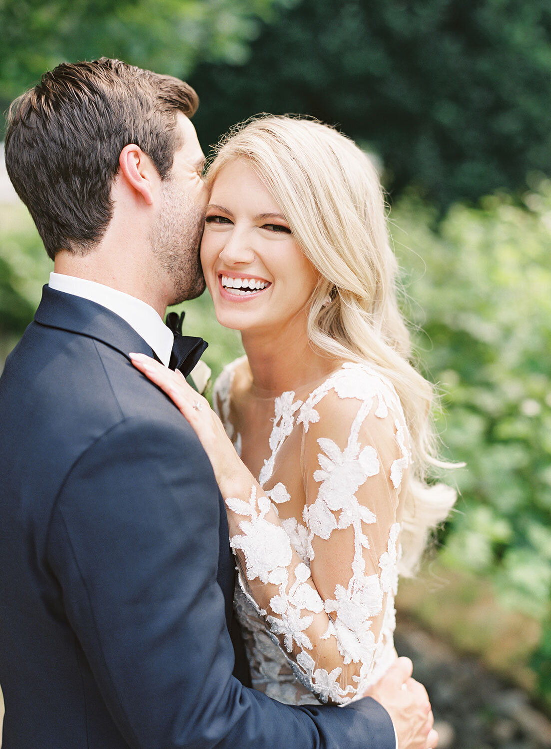 Bride laughing as groom whispers to her