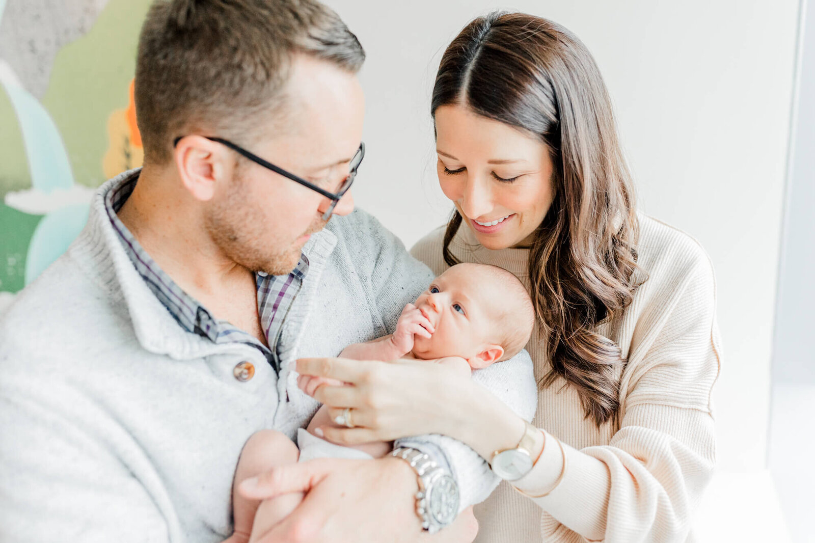 Newborn looks up at his dad while mom and dad smile down at him