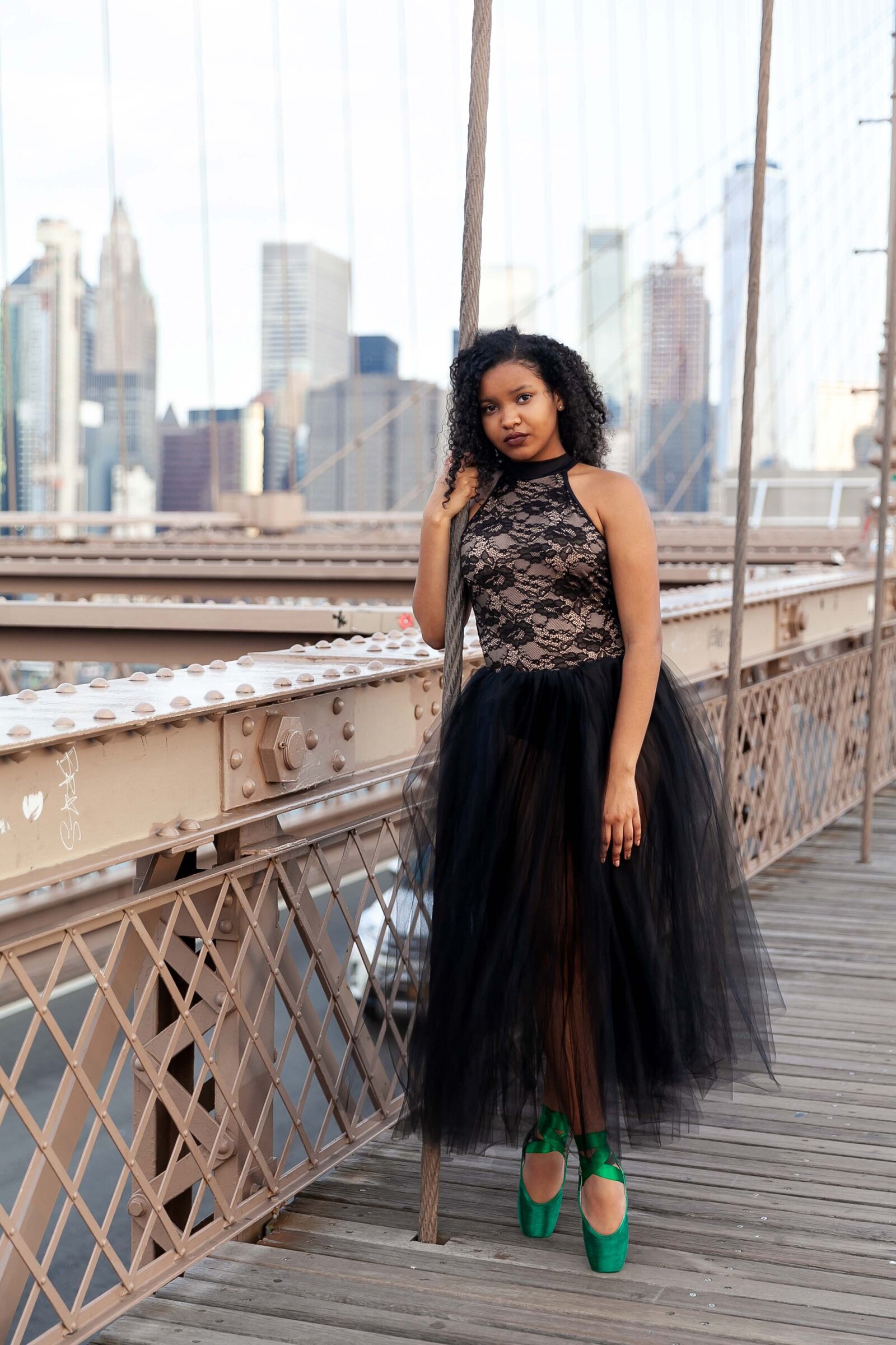 Black ballerina in romantic tutu and green pointe shoes standing on Brooklyn Bridge