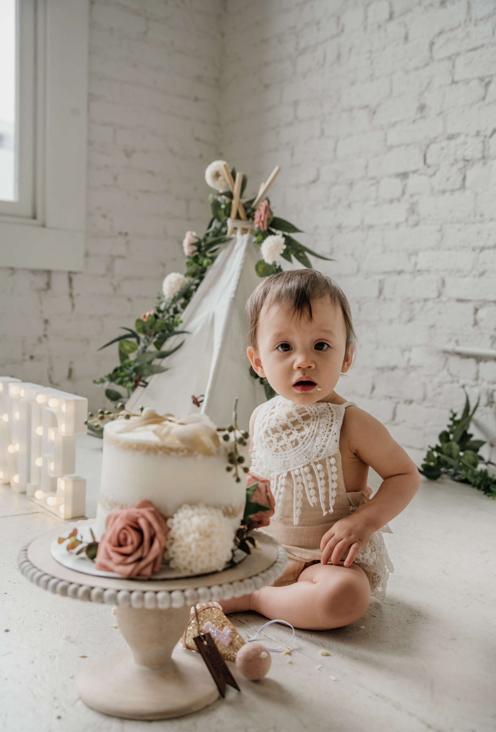 Baby girl sitting in studio with her cake.