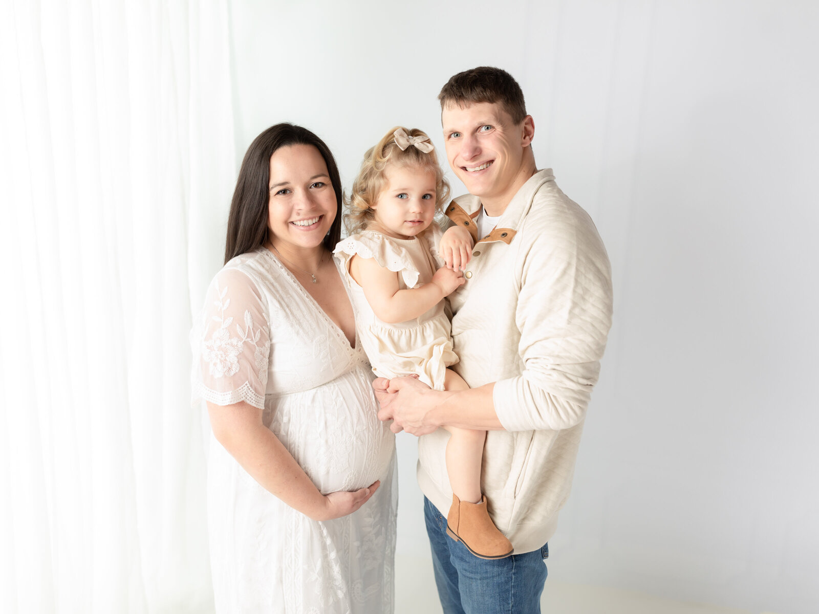 husband and wife holding daughter for maternity photoshoot