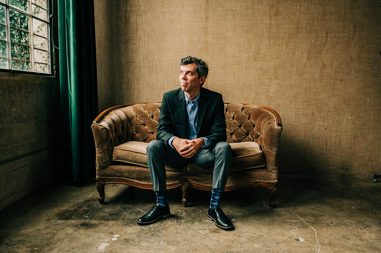 moody portrait of man in a suit sitting on a couch