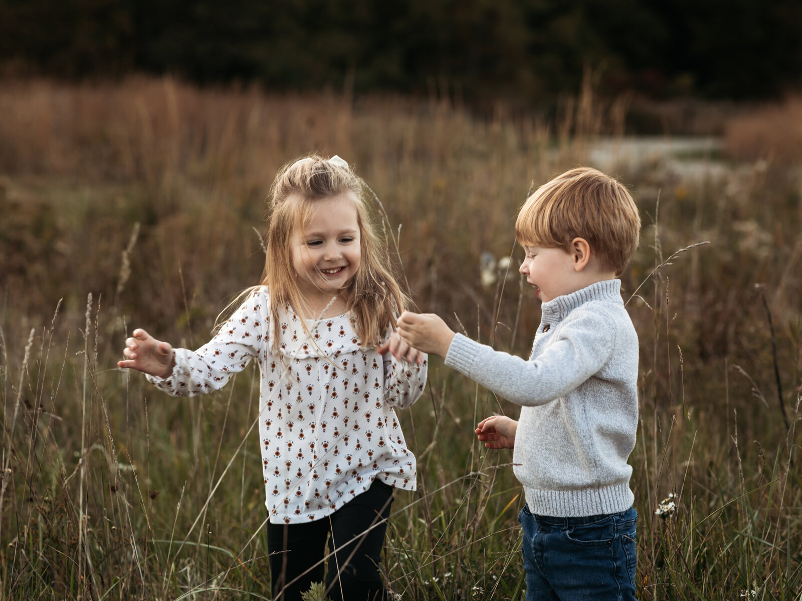 brother and sister playing in field for family photos 