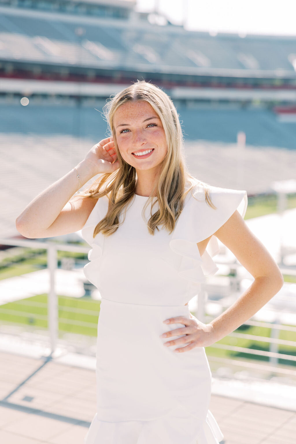 Girl in white dress smiles at UGA Stadium