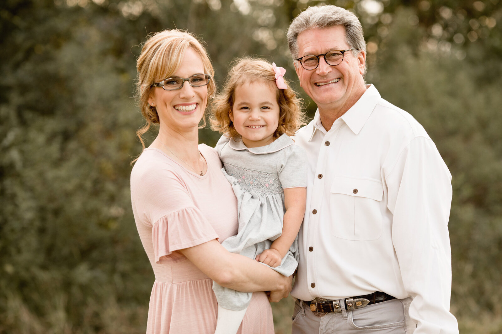 Carolyn Teague smiles while holding her daughter next to her husband in family portrait