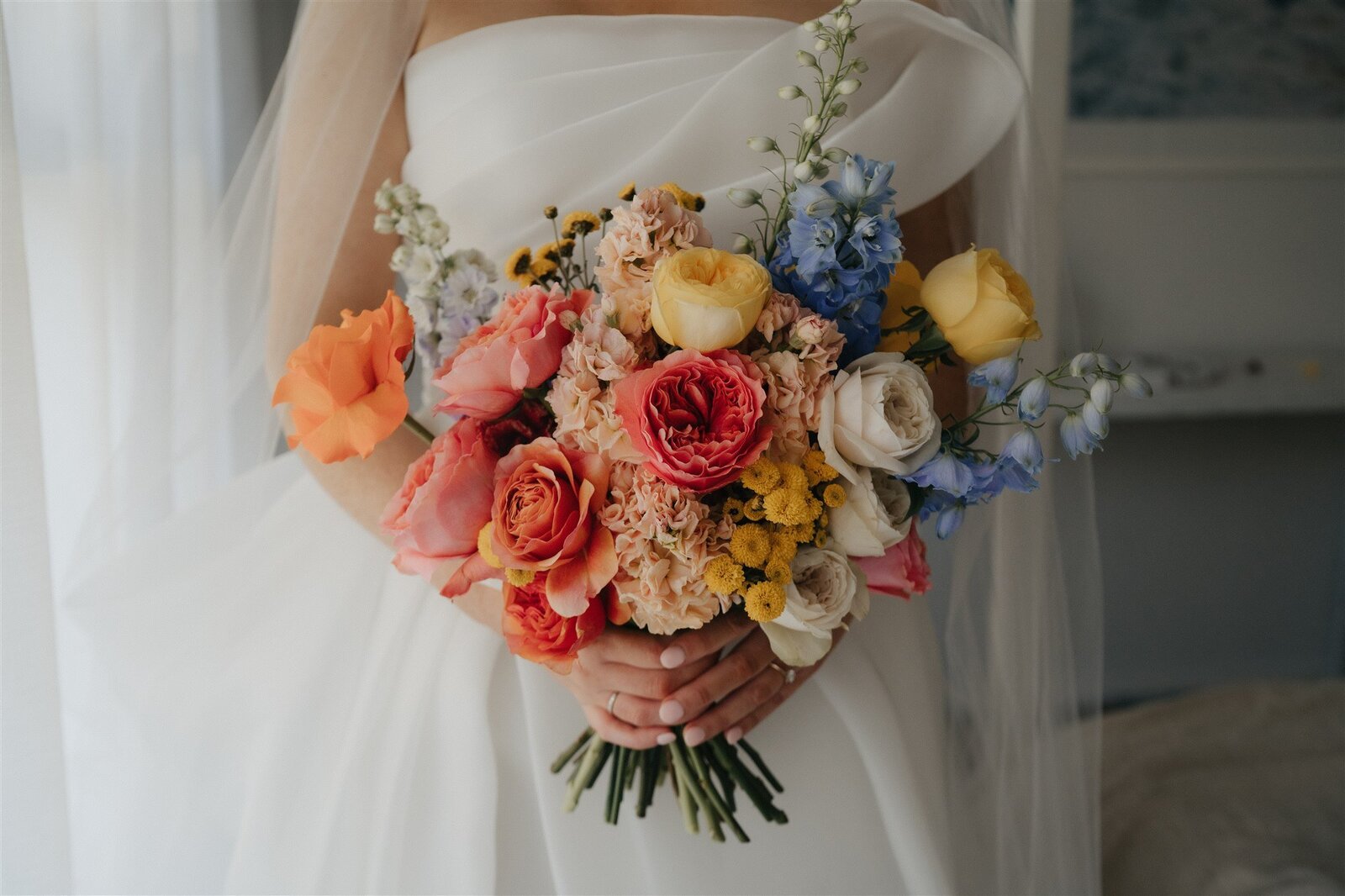 Wedding bouquet of colourful. flowers held in front of bride