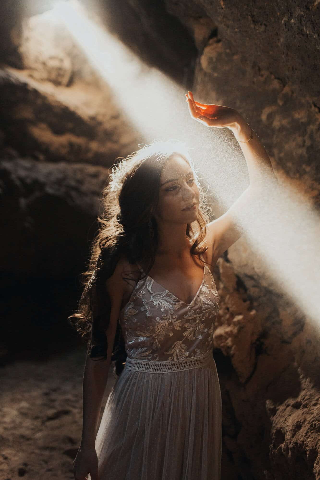 A bride is bathed in a beam of light while underground in a California Cave on her wedding day. 