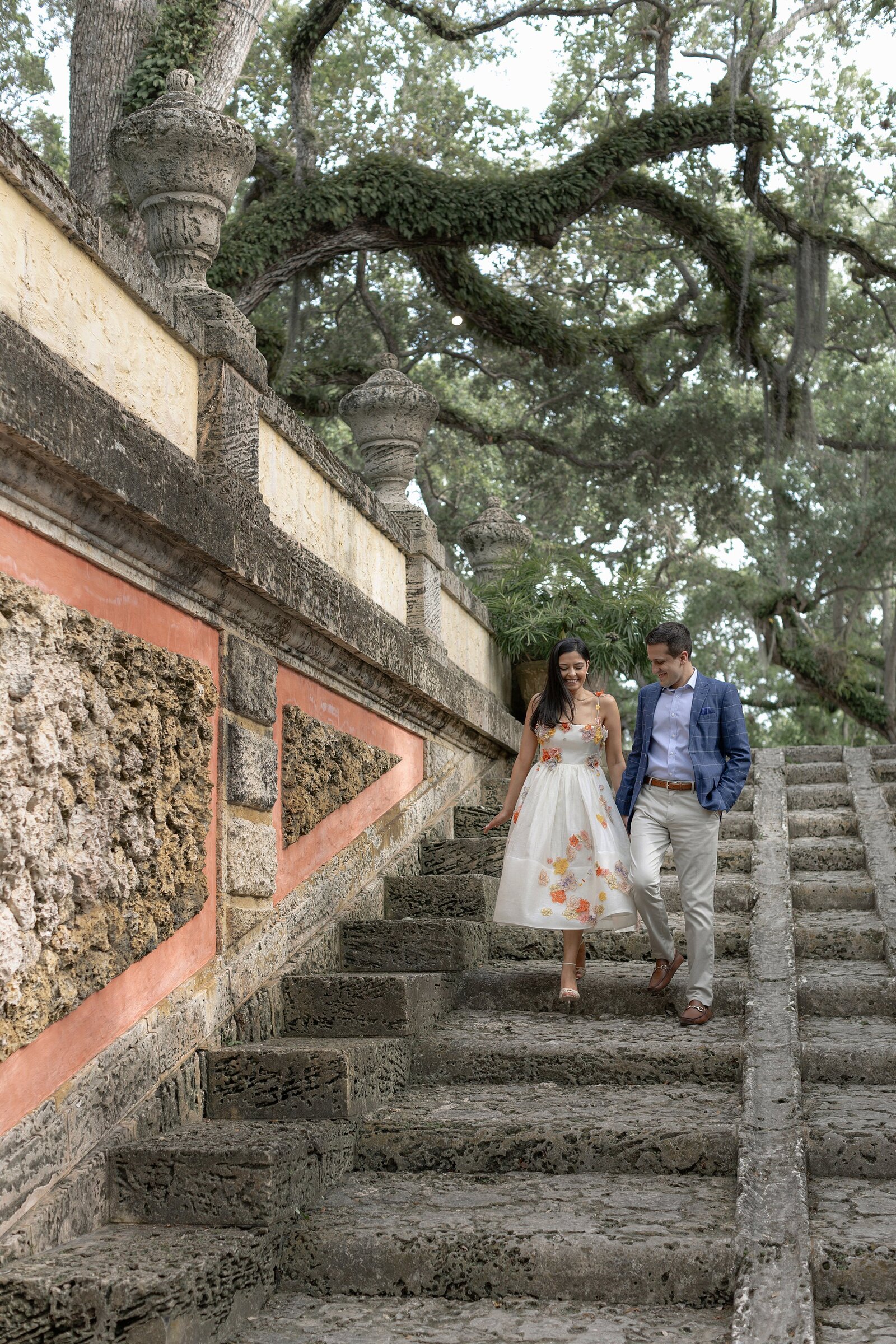 Couple walk hand in hand down stone steps at Vizcaya Museum Miami.