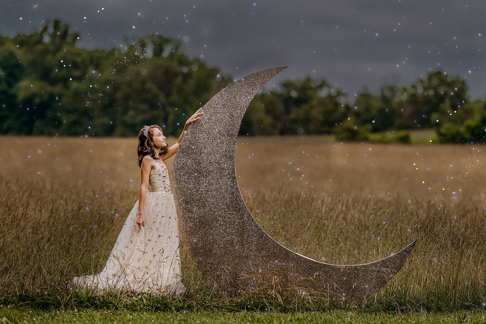 Girl in champagne gown with stars standing next to giant cresecent moon in a field at Jerusalem Mill in Kingsville Maryland