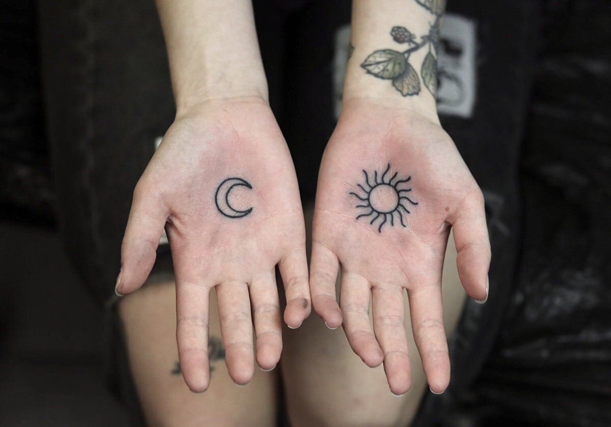 Tatuering i handflator av måne och sol.