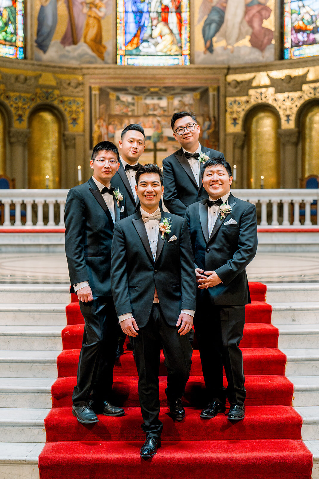 The groom and his groomsmen share a fun moment on the steps of Stanford Memorial Church, adding a touch of lightheartedness to the elegant wedding day.
