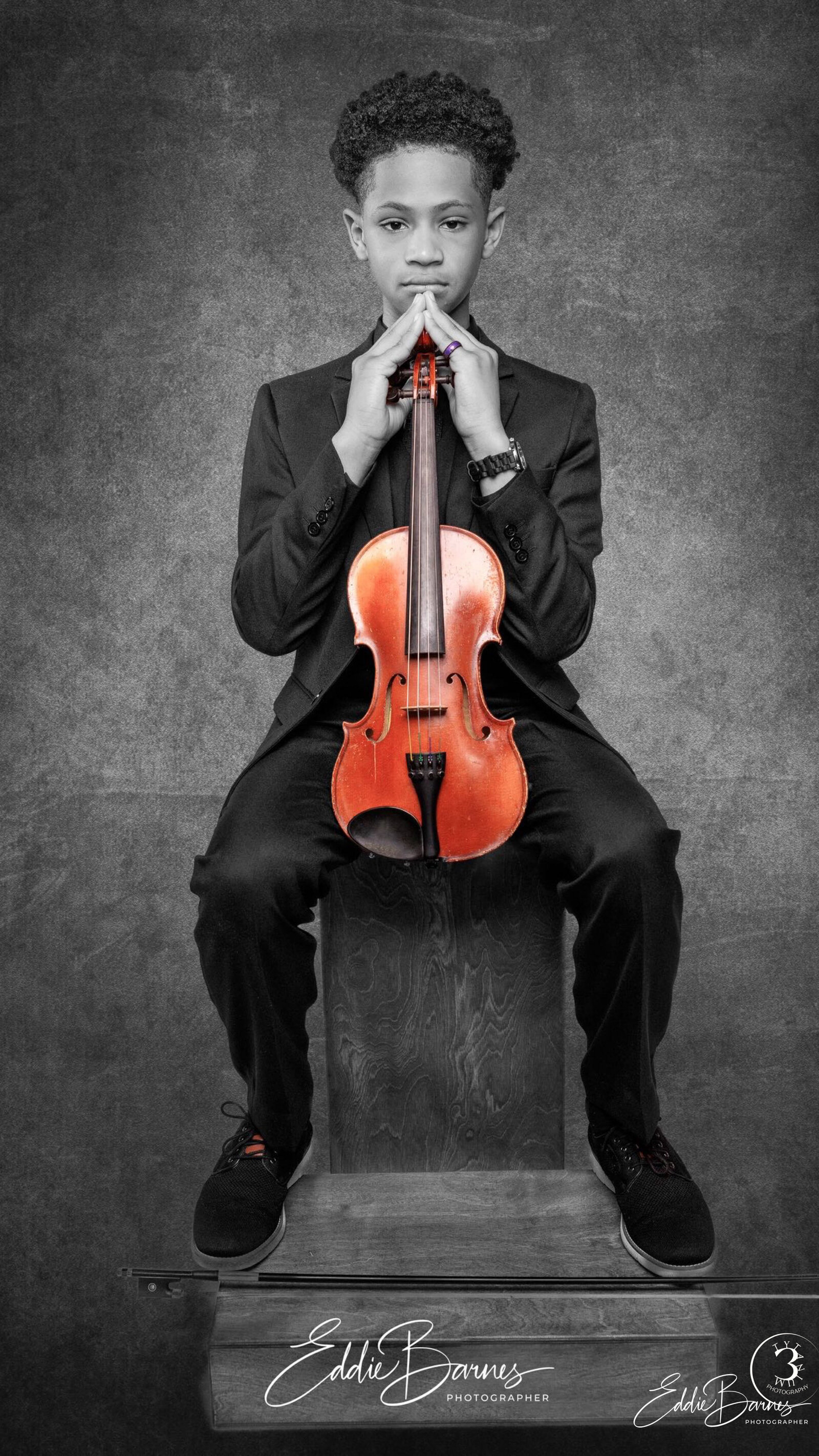 Studio portrait of a young male violinist wearing a black suit and holding a violin, photographed by Tytanium3 Photography in Greenville, SC.