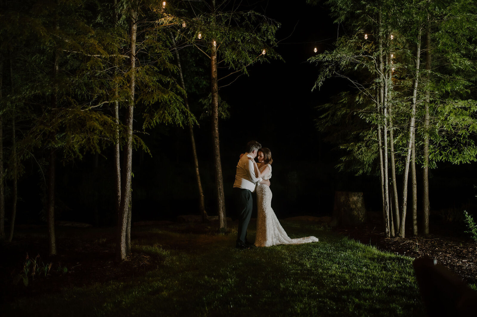 couple dancing under string lights in the forest wedding first dance
