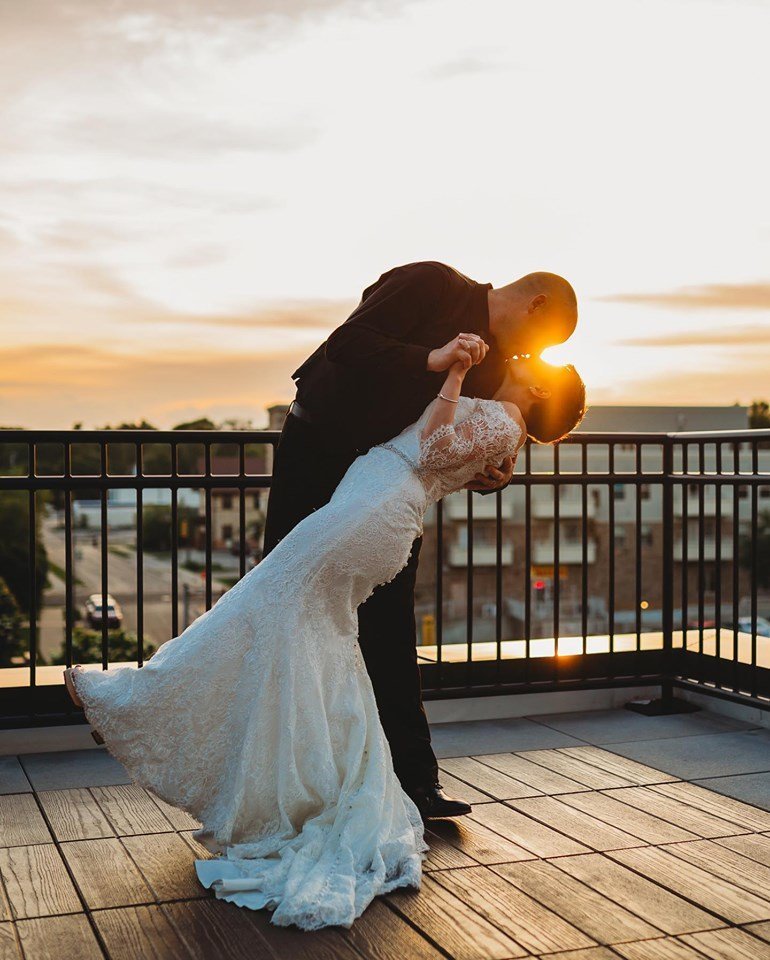 Husband and wife kissing on a rooftop at sunset